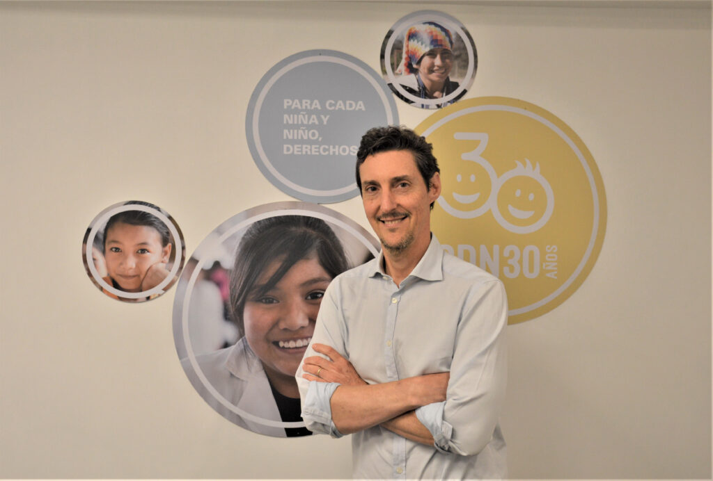 Martin Gimenez-Rebora standing in front of images of children