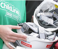 Buckets of old mobile phones held by ChildLine volunteers wearing the charity's green tshirt