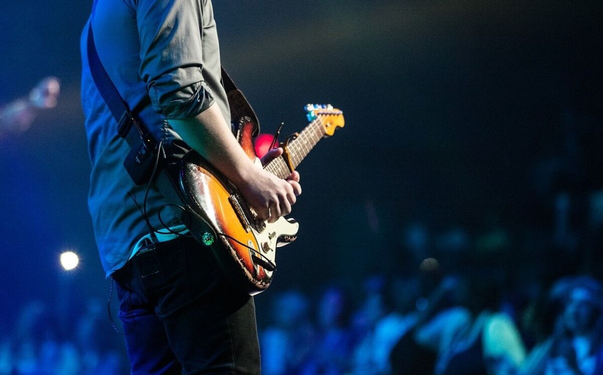 a man plays guitar on a stage in front of an audience