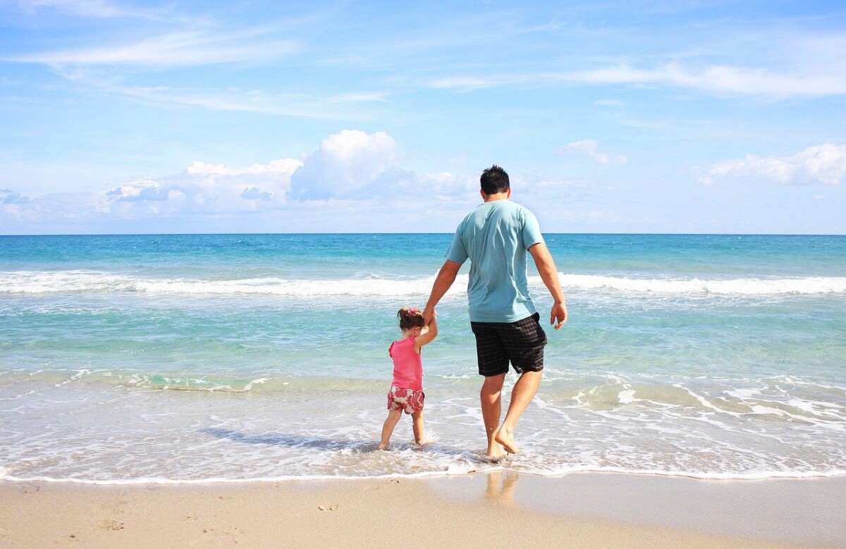 A man and his toddler daughter paddle in a turquoise sea. By sarahbernier3140 from Pixabay