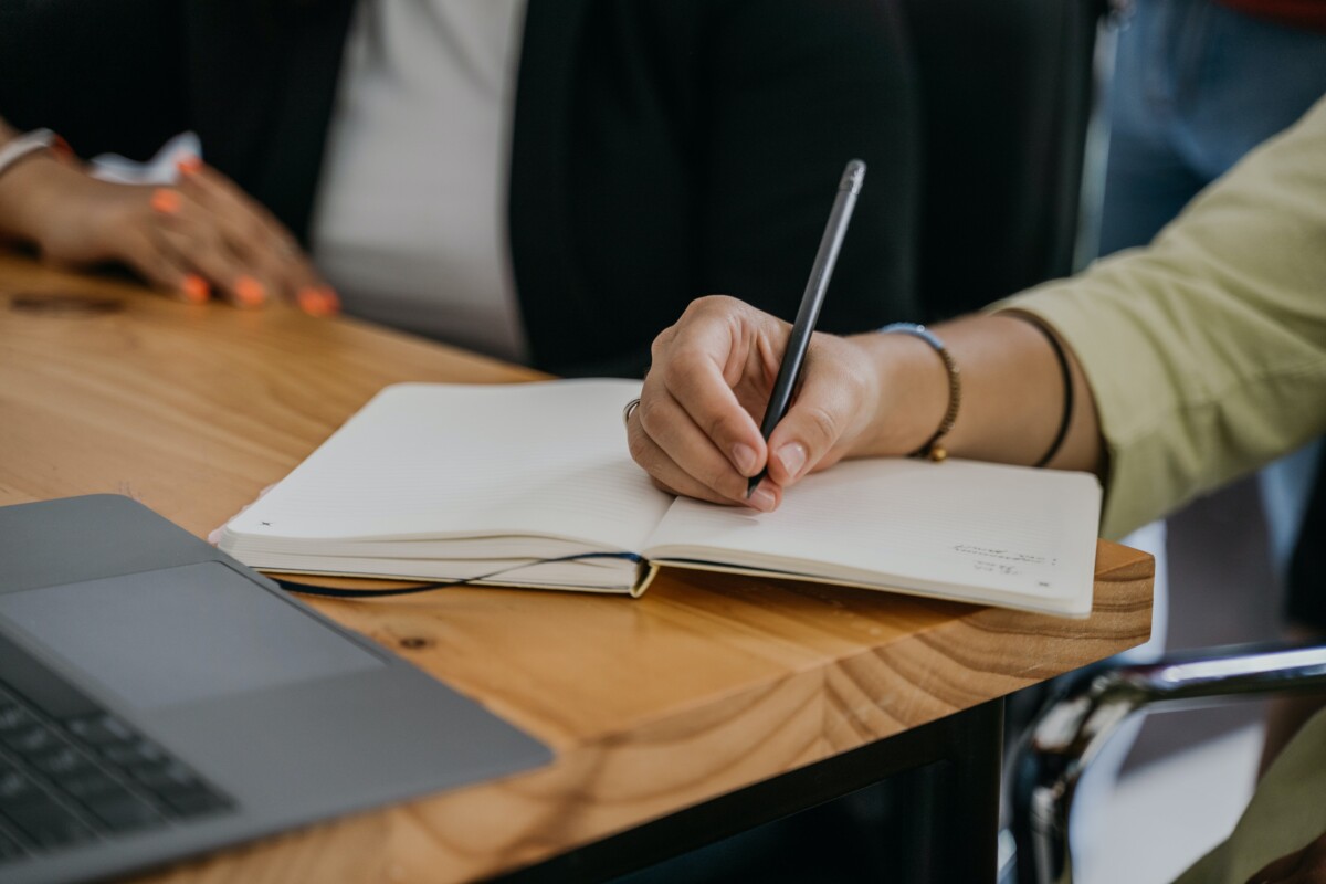 A woman's hand writes in a notebook