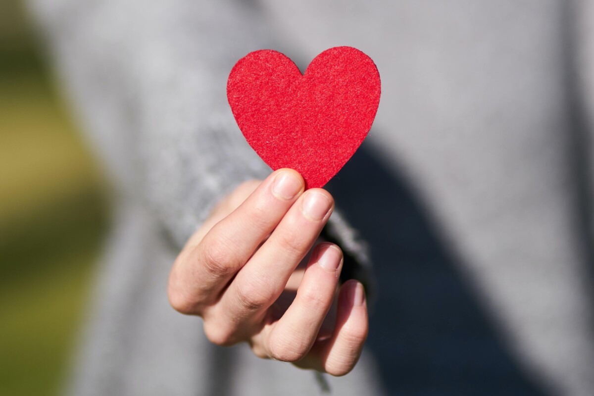 A woman's heart holds out a red heart. By Engin Akyurt on Pexels