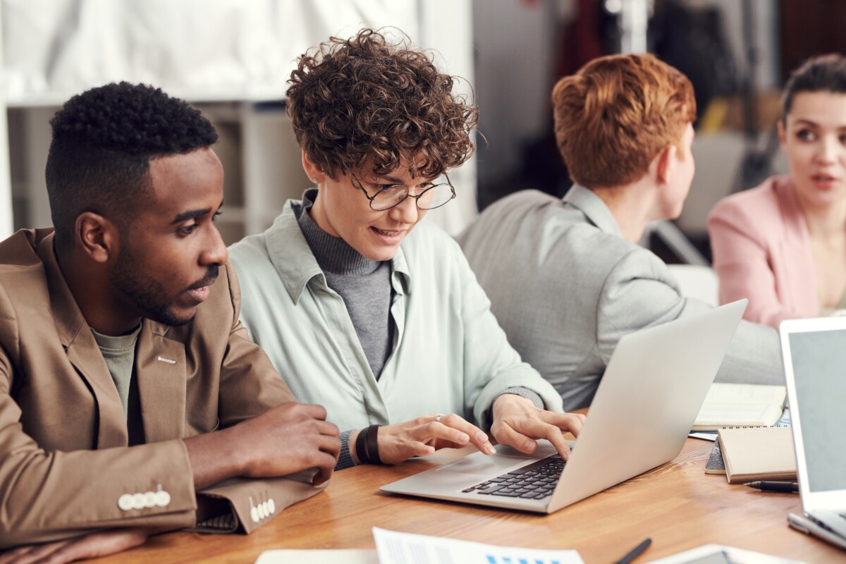 three men and a woman working in an office with laptops