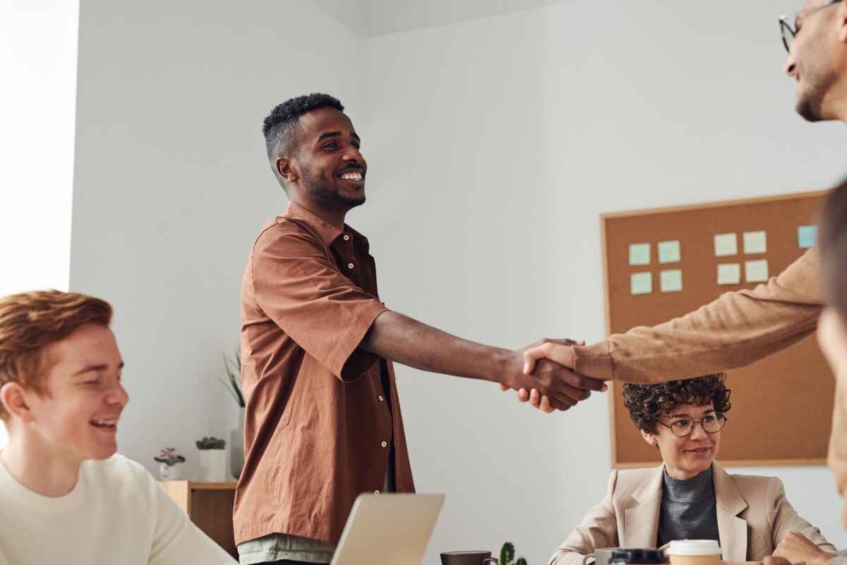two men shaking hands over a table in an office