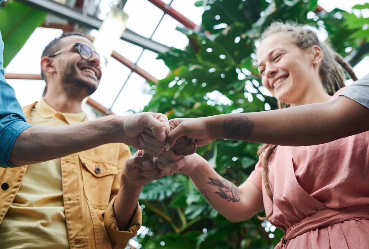 4 people bump fists. By Fauxels on Pexels