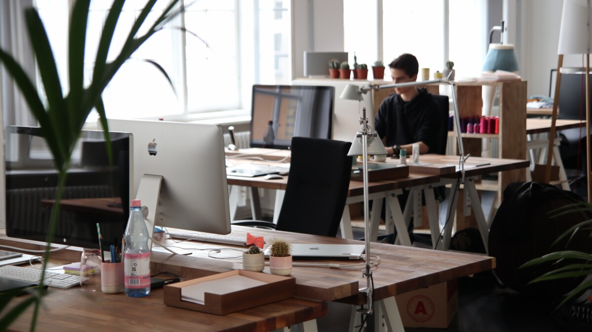 Office scene with computers & desks and one young male office worker