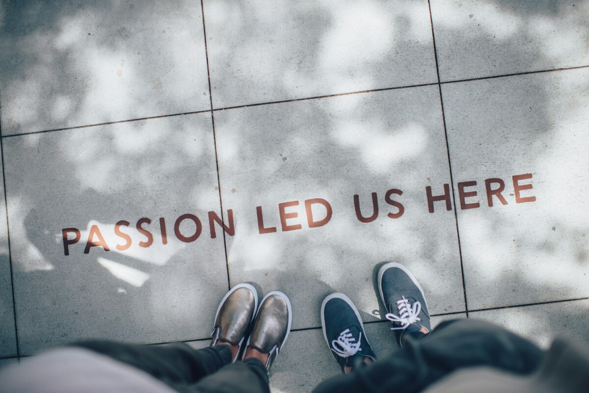 "Passion led us here". Text inscribed in paving stones, looked at by two people.